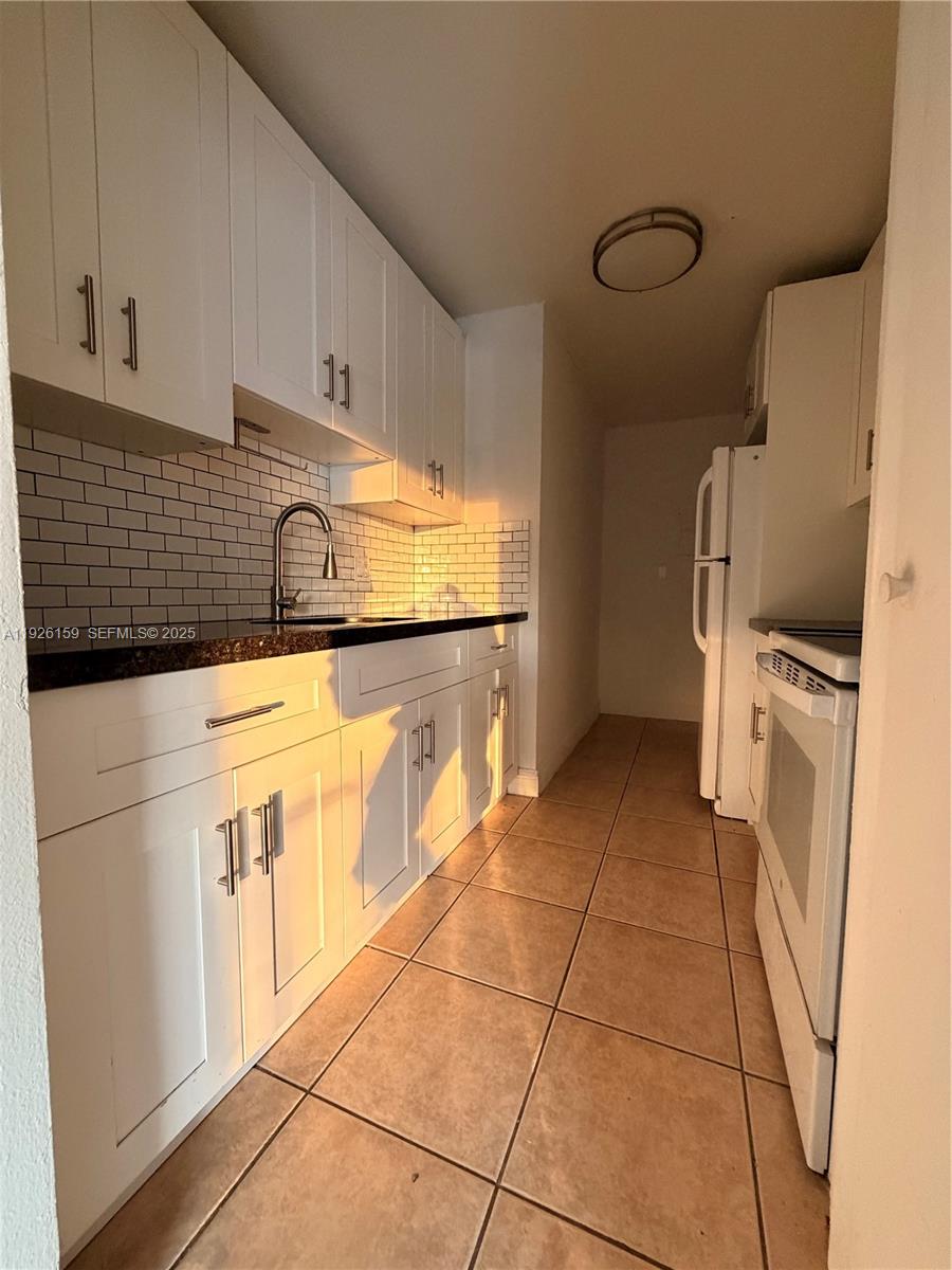 7250 Southwest 94th Place, Unit B8 Miami, FL 33173 - Photo 6 of 18 a kitchen with granite countertop a stove a sink and a refrigerator
