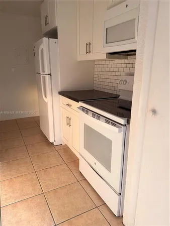 a kitchen with white cabinets and white appliances