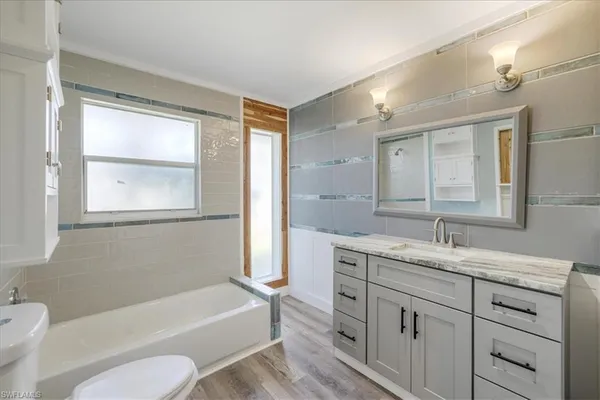 a bathroom with a granite countertop sink toilet tub and mirror