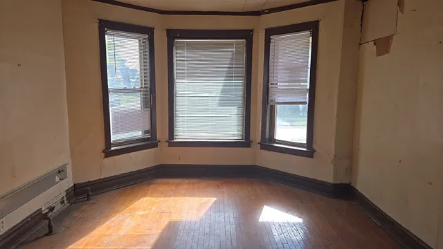 a view of an empty room with wooden floor and a window