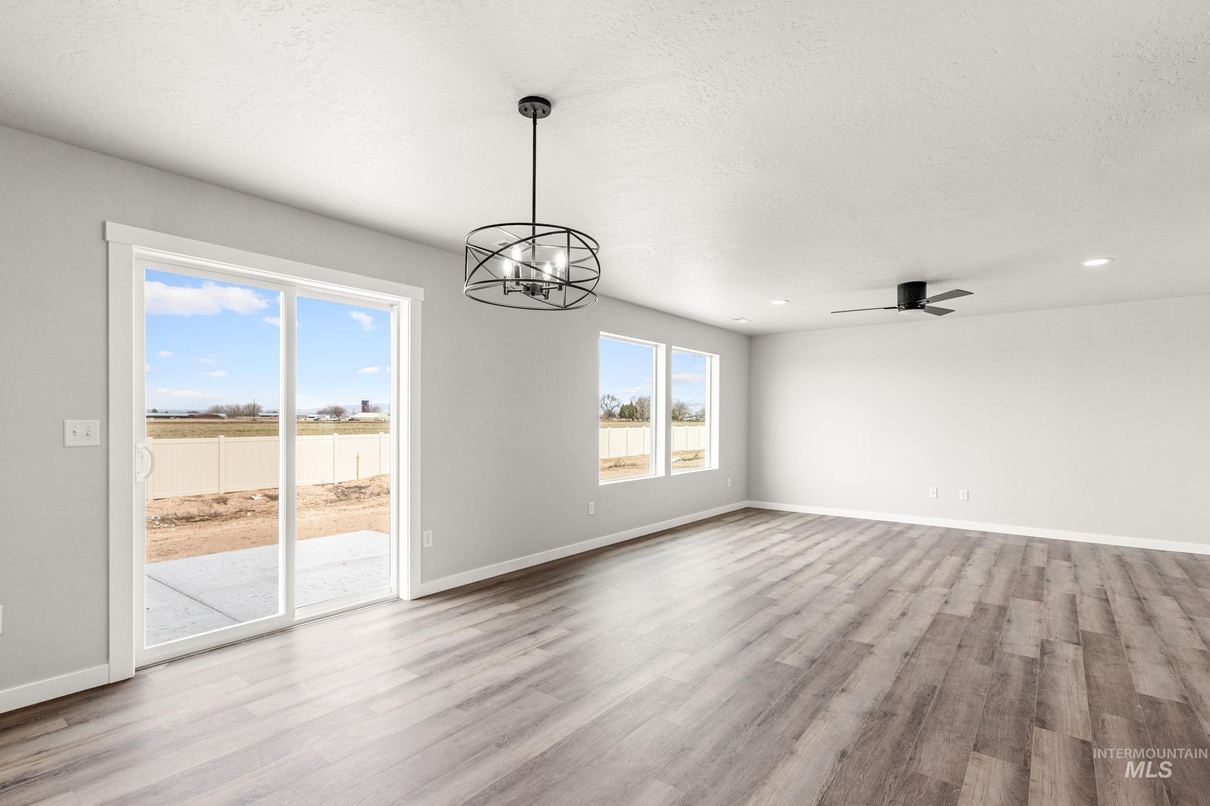 12830 Ropers Street Nampa, ID 83651 - Photo 6 of 18 Spacious room featuring wood-finish flooring, light gray walls, and multiple windows