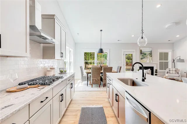 a kitchen with stainless steel appliances granite countertop a sink a stove a refrigerator and island with wooden floor