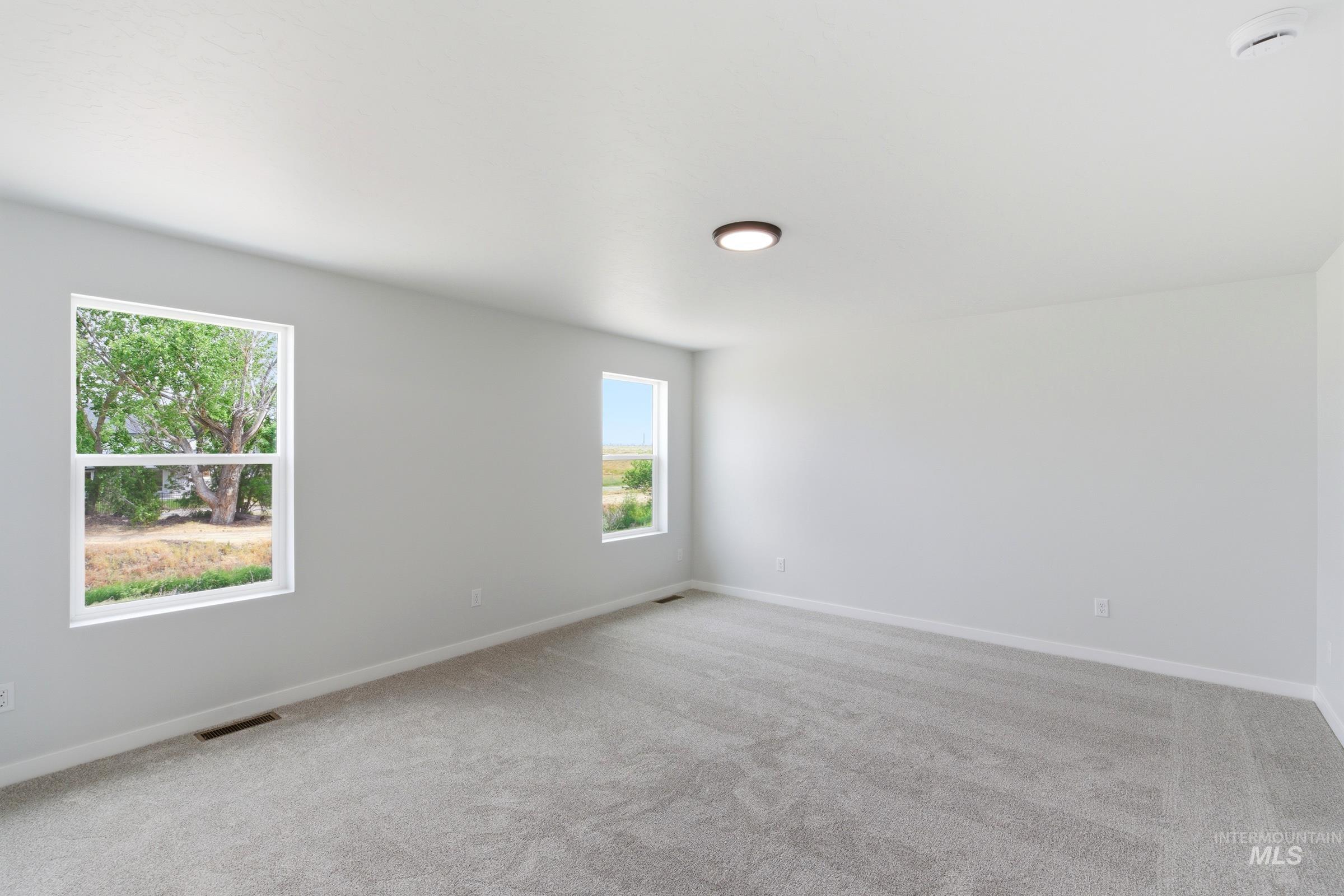 12829 Decatur Street Nampa, ID 83651 - Photo 27 of 33 Spacious room featuring light gray carpeting, neutral wall paint, white trim, and two double-hung windows