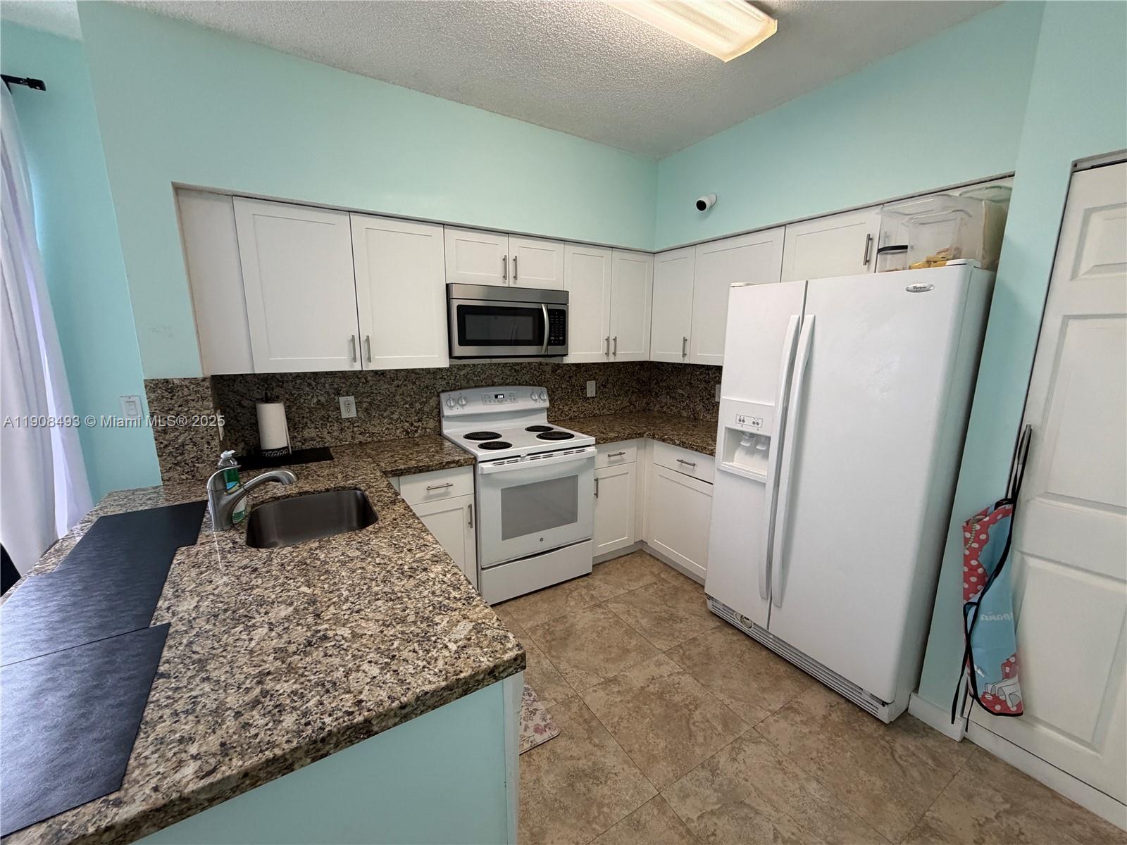 810 Northeast 212th Terrace, Unit 2 Miami, FL 33179 - Photo 11 of 44 a kitchen with a refrigerator a stove top oven a sink and dishwasher
