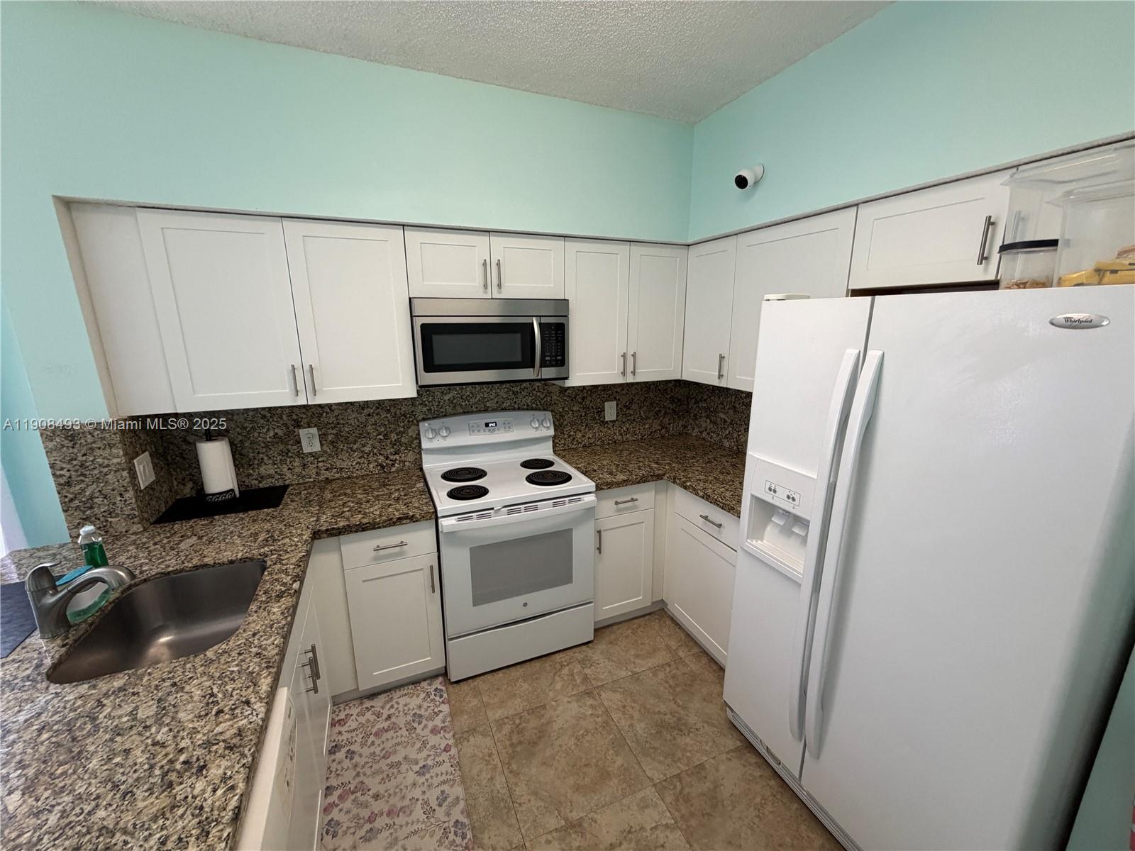 810 Northeast 212th Terrace, Unit 2 Miami, FL 33179 - Photo 13 of 44 a kitchen with a refrigerator stove and microwave