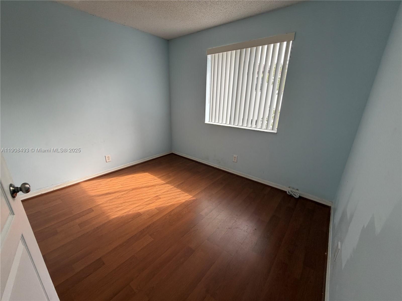 810 Northeast 212th Terrace, Unit 2 Miami, FL 33179 - Photo 20 of 44 an empty room with wooden floor and windows