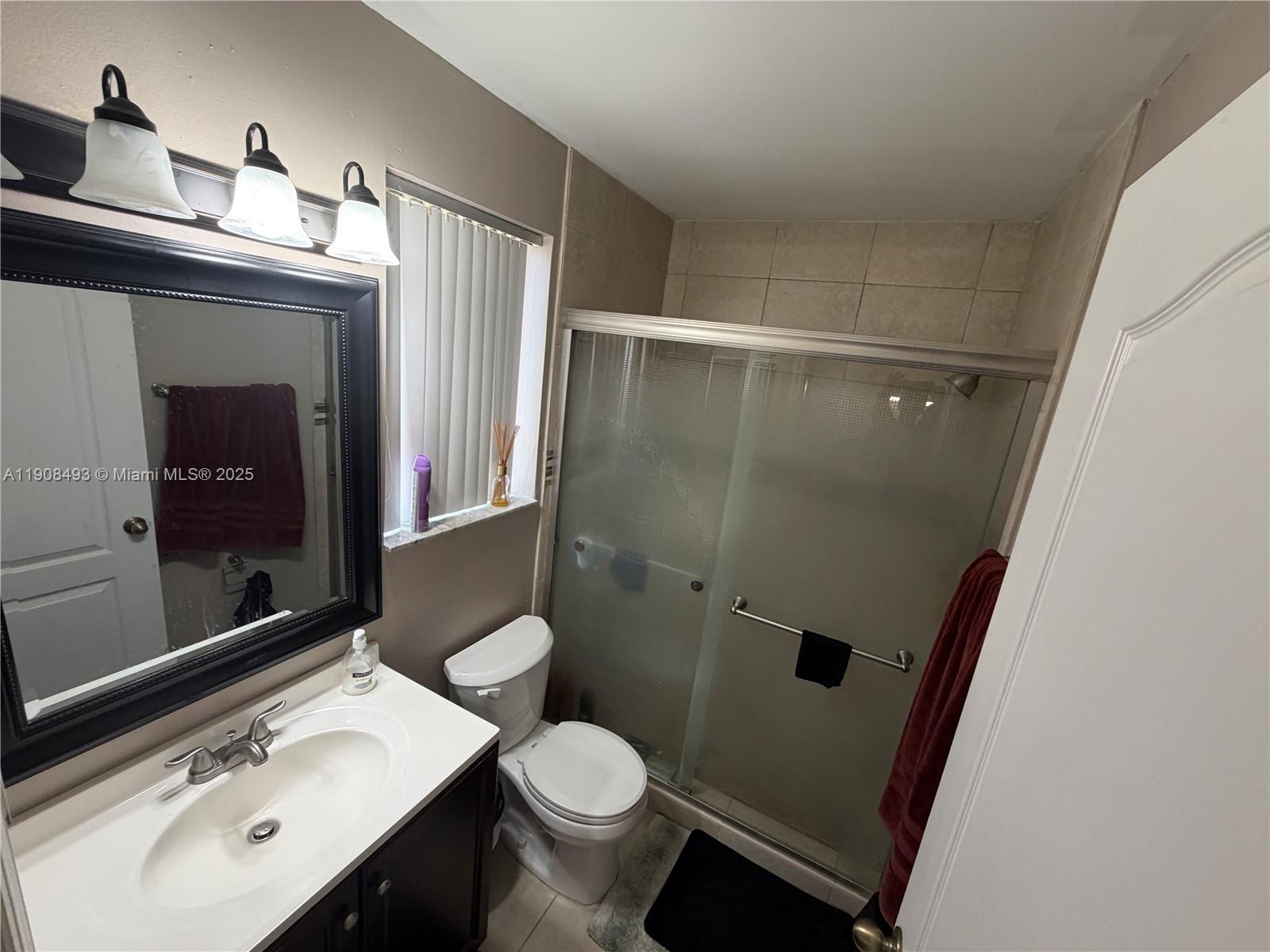 810 Northeast 212th Terrace, Unit 2 Miami, FL 33179 - Photo 24 of 44 a bathroom with a sink vanity mirror and toilet
