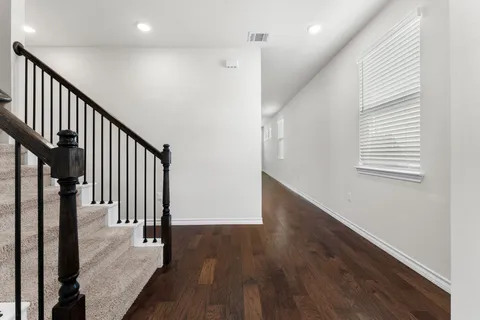 a view of a hallway with wooden floor and staircase
