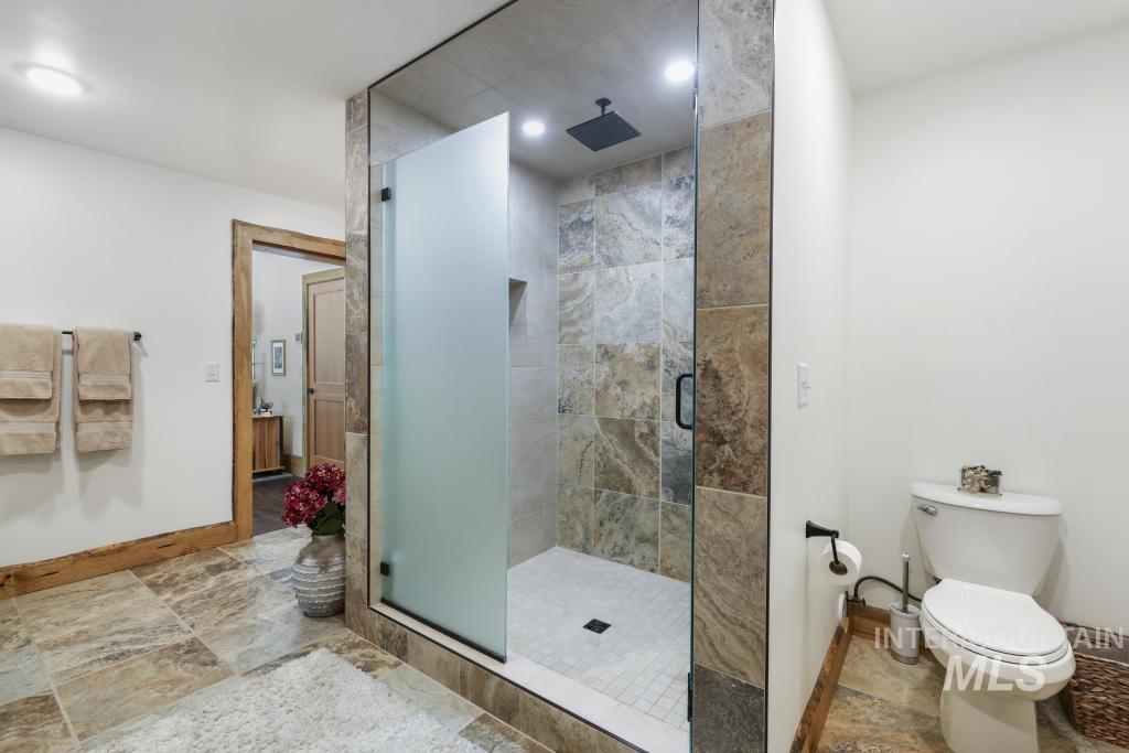 65 Goat Creek Way Stanley, ID 83278 - Photo 23 of 32 Walk-in shower with natural stone-look tiling and a matte black rainfall showerhead