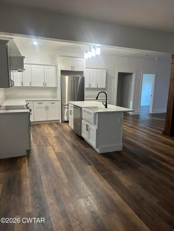 a living room with stainless steel appliances furniture a refrigerator and wooden floor