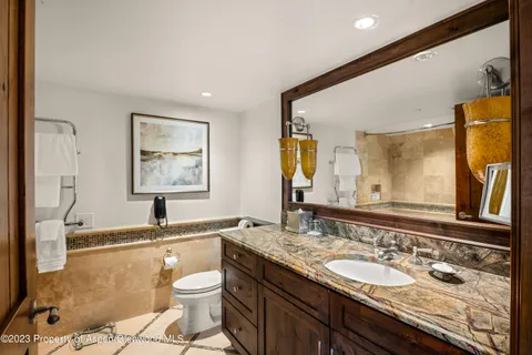 a bathroom with a granite countertop sink mirror vanity and toilet