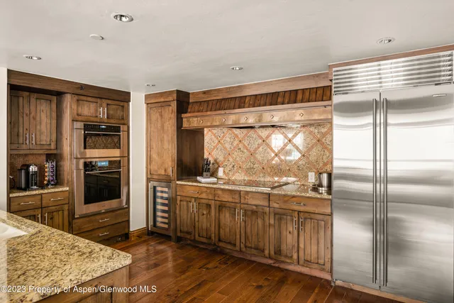 a kitchen with stainless steel appliances granite countertop a refrigerator a oven a sink and dishwasher with wooden floor