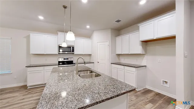 a kitchen with kitchen island granite countertop stainless steel appliances sink and cabinets