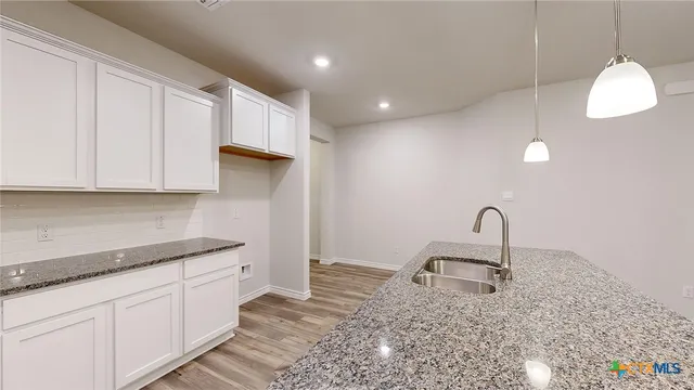 a kitchen with granite countertop a sink a counter top space and cabinets