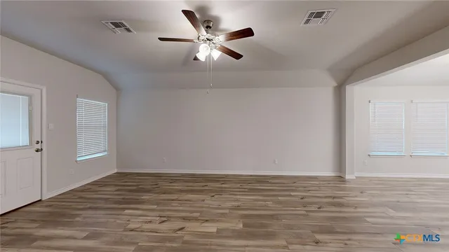 a view of empty room with wooden floor and fan