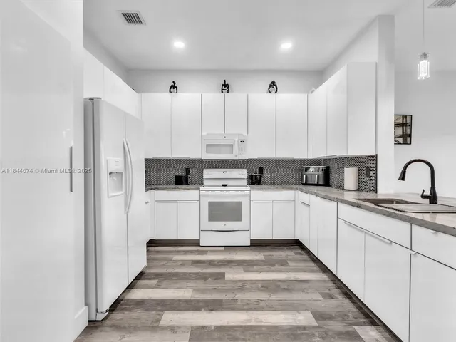 a kitchen with white cabinets and white appliances