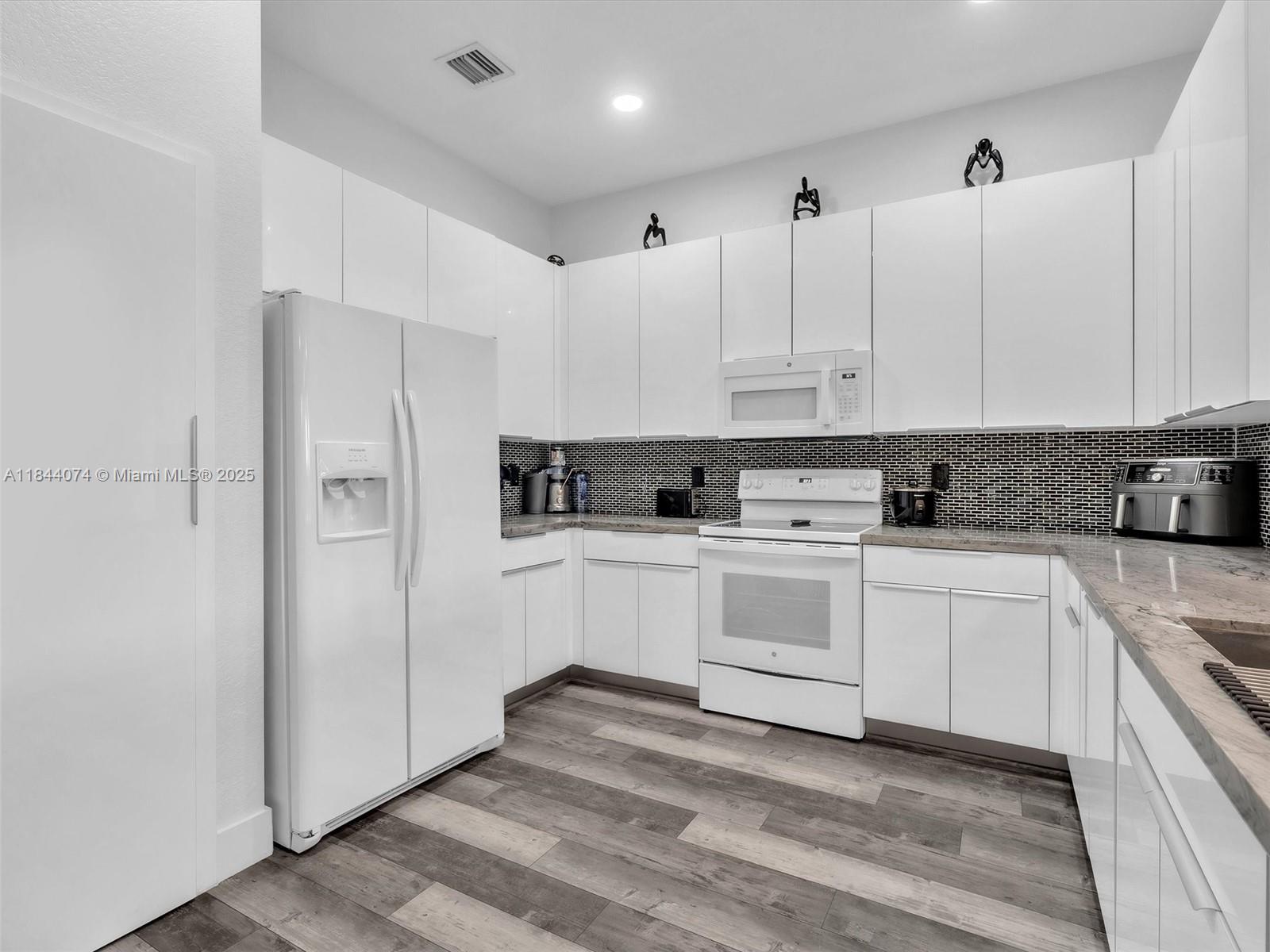 4331 Southwest 124th Way Miramar, FL 33027 - Photo 10 of 58 a kitchen with stainless steel appliances granite countertop a refrigerator sink and white cabinets