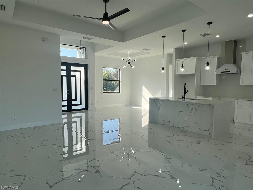 3510 15th Street Southwest Lehigh Acres, FL 33976 - Photo 15 of 50 Kitchen with white cabinets, wall chimney exhaust hood, sink, and decorative light fixtures