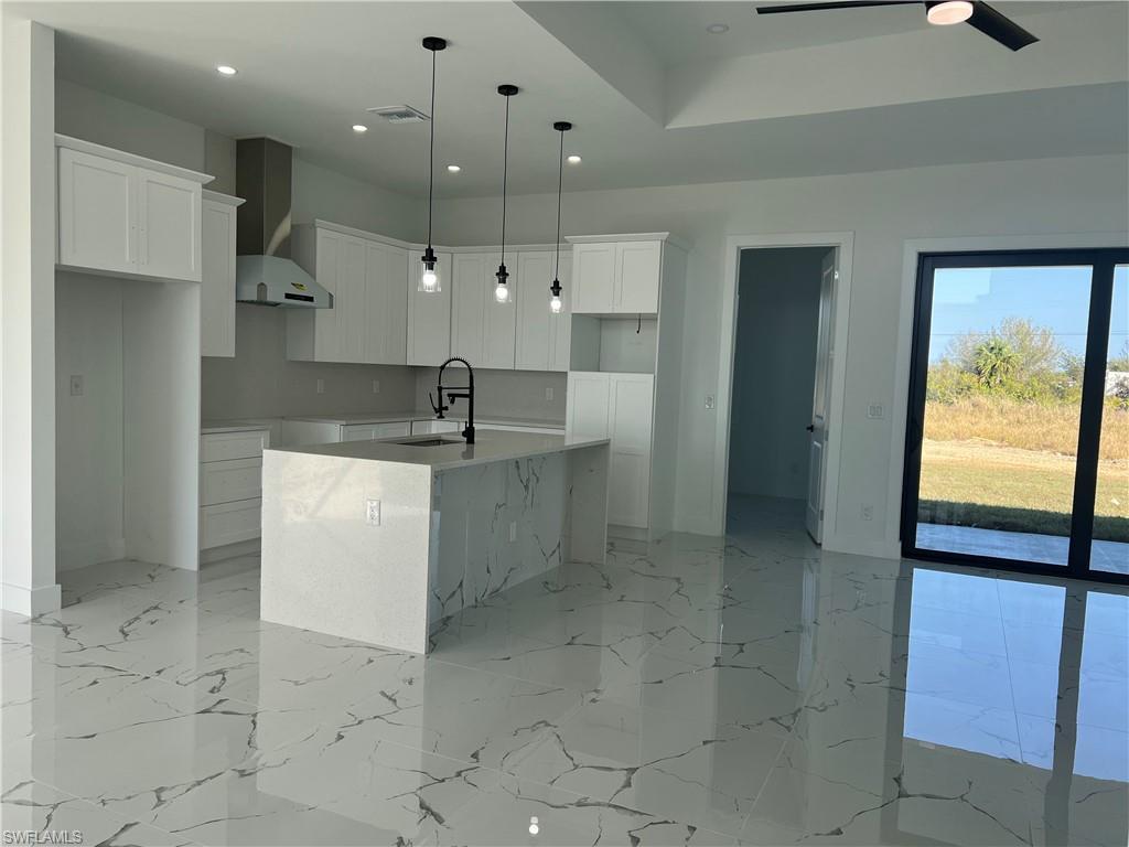3510 15th Street Southwest Lehigh Acres, FL 33976 - Photo 17 of 50 Kitchen with a kitchen island with sink, white cabinets, sink, hanging light fixtures, and wall chimney exhaust hood