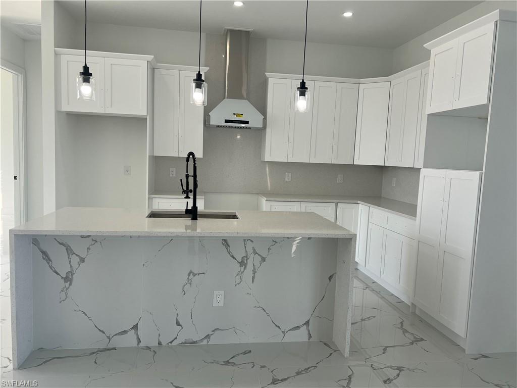 3510 15th Street Southwest Lehigh Acres, FL 33976 - Photo 18 of 50 Kitchen featuring pendant lighting, wall chimney exhaust hood, and a kitchen island with sink
