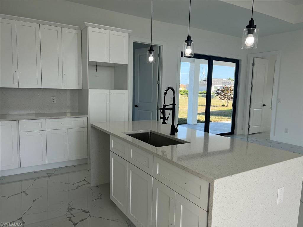 3510 15th Street Southwest Lehigh Acres, FL 33976 - Photo 19 of 50 Kitchen featuring light stone counters, a kitchen island with sink, sink, decorative light fixtures, and white cabinetry