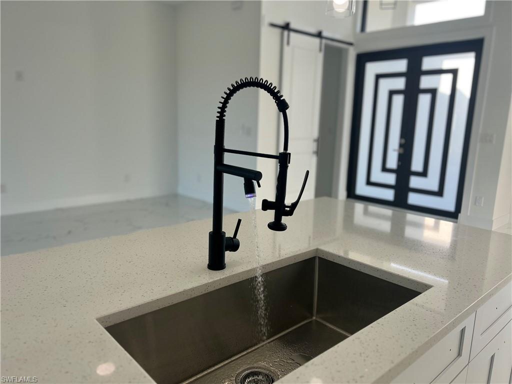 3510 15th Street Southwest Lehigh Acres, FL 33976 - Photo 20 of 50 Details featuring white cabinetry, a barn door, light stone counters, and sink