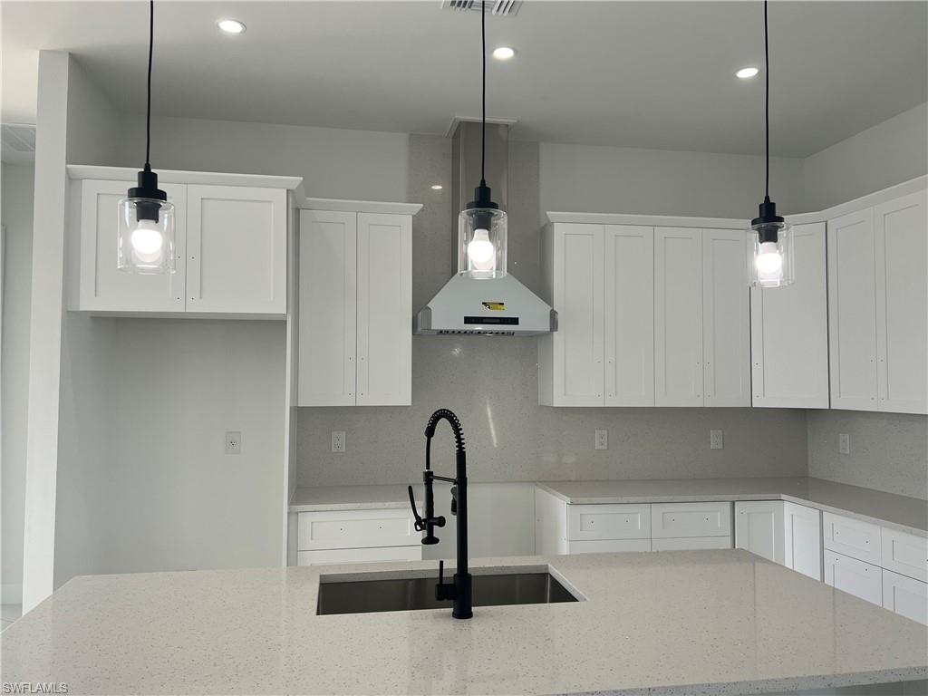 3510 15th Street Southwest Lehigh Acres, FL 33976 - Photo 21 of 50 Kitchen with light stone countertops, decorative light fixtures, and white cabinetry