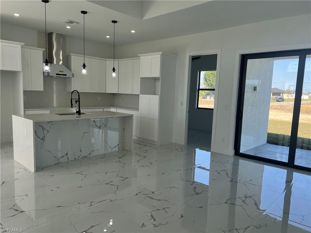 3510 15th Street Southwest Lehigh Acres, FL 33976 - Photo 27 of 50 Kitchen with white cabinets, a center island with sink, wall chimney range hood, and sink