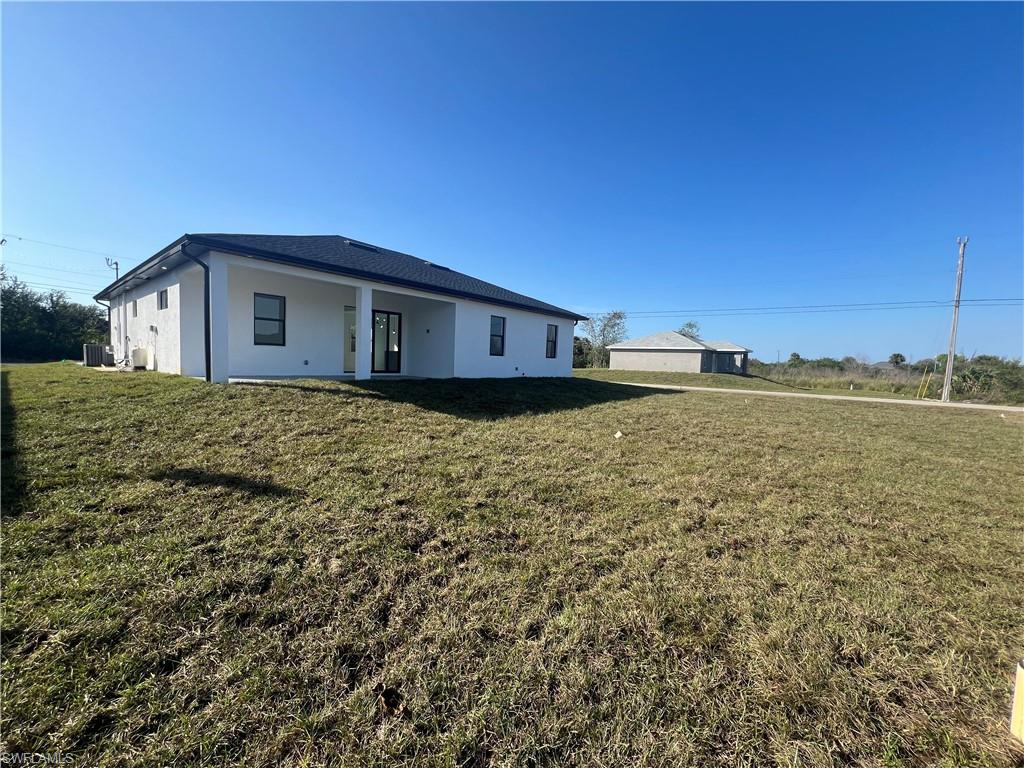 3510 15th Street Southwest Lehigh Acres, FL 33976 - Photo 39 of 50 Back of property featuring a yard and cooling unit