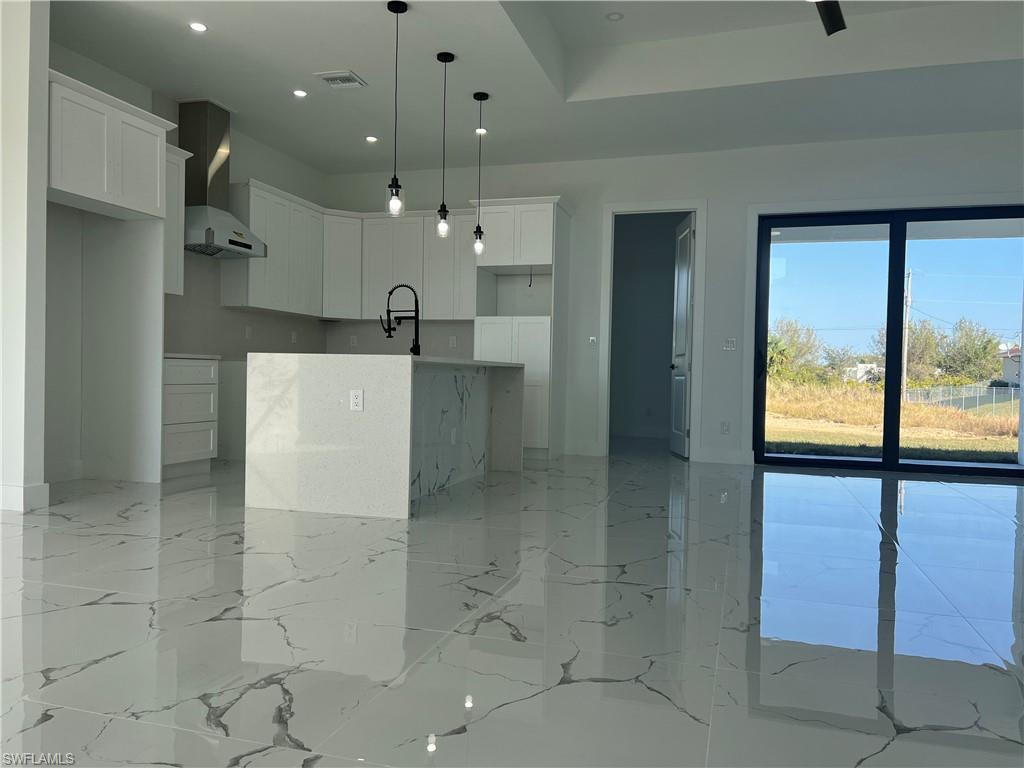 3510 15th Street Southwest Lehigh Acres, FL 33976 - Photo 9 of 50 Kitchen with white cabinets, wall chimney exhaust hood, pendant lighting, and a center island