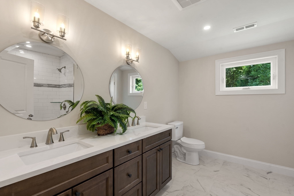 1 Emmeline Path, Unit 1 Wayland, MA 01778 - Photo 16 of 22 a bathroom with a double vanity sink toilet and a mirror