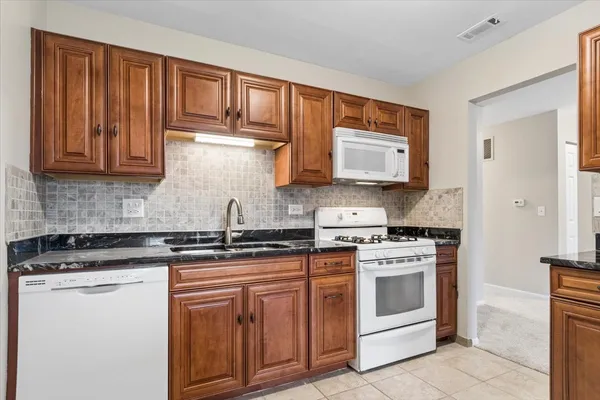 a kitchen with stainless steel appliances granite countertop a stove a sink and a microwave