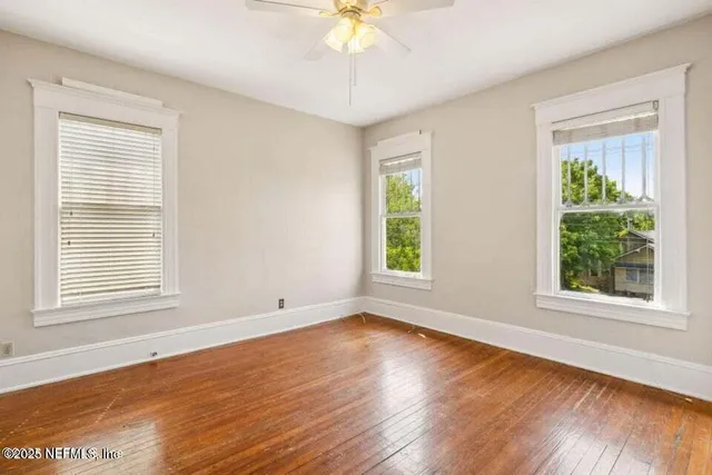 a view of an empty room with wooden floor and a window