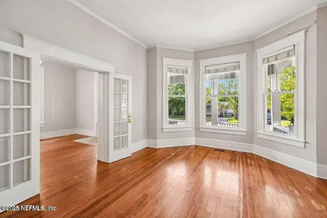 an empty room with wooden floor and windows