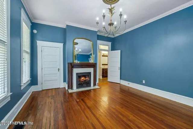 a view of a livingroom with wooden floor a fireplace and windows