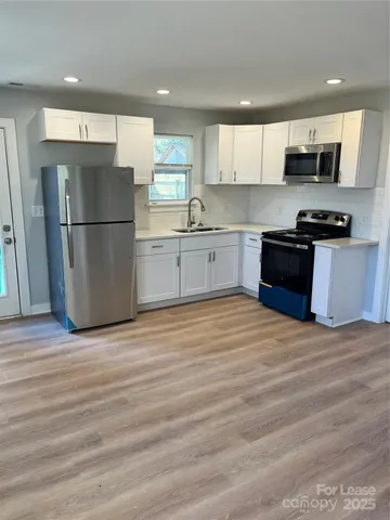 a kitchen with stainless steel appliances granite countertop a refrigerator sink and white cabinets