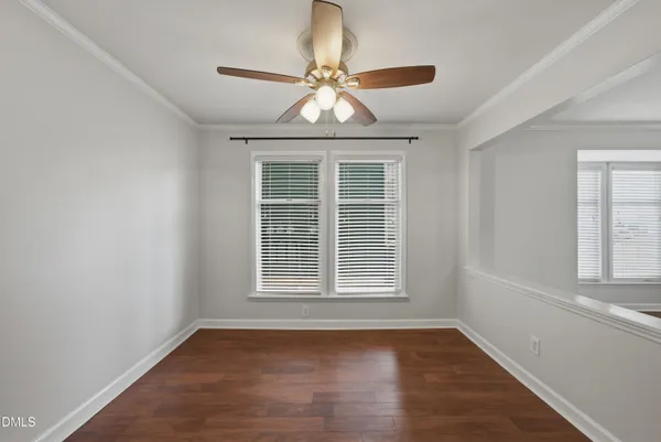 an empty room with wooden floor chandelier and window