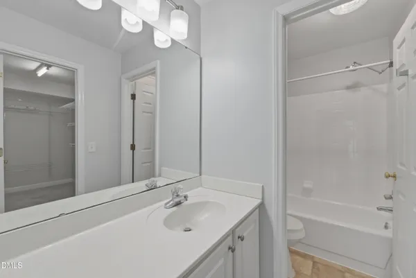 a bathroom with a tub sink vanity granite and mirror