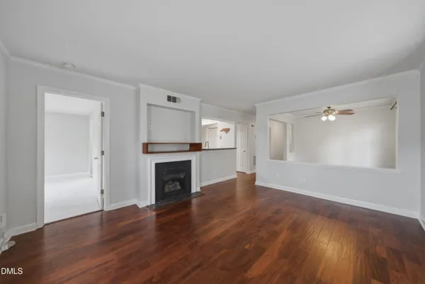 a view of empty room with wooden floor and kitchen