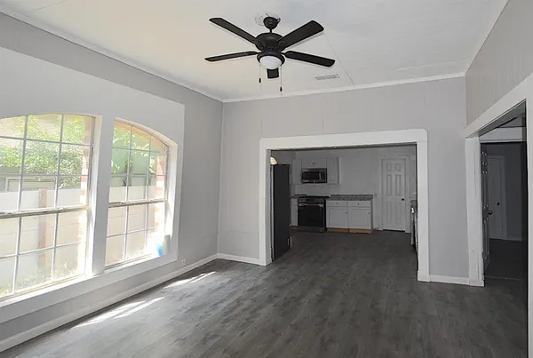 a view of an empty room with a window and a kitchen