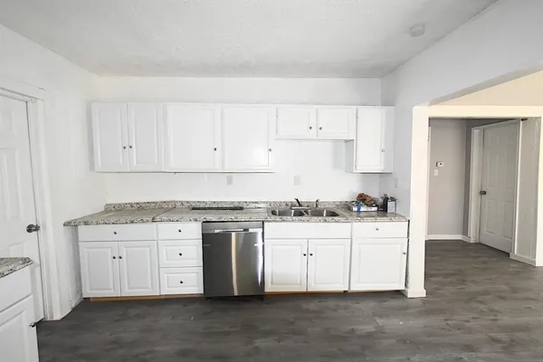 a kitchen with granite countertop a sink stove and cabinets