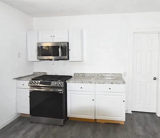 a kitchen with granite countertop cabinets stainless steel appliances and wooden floor