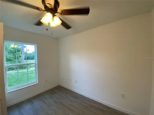 an empty room with a window and a fan