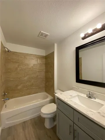 a bathroom with a granite countertop sink a toilet and a bathtub