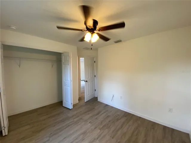 an empty room with wooden floor ceiling fan and window