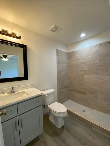 a bathroom with a granite countertop sink a toilet and a mirror