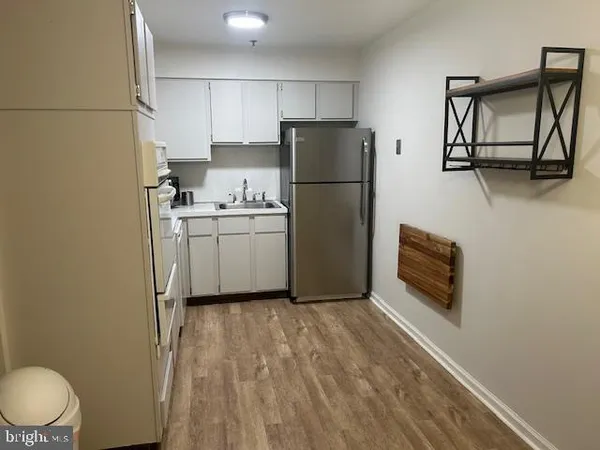 a kitchen with a refrigerator a stove top oven a counter space and wooden floor