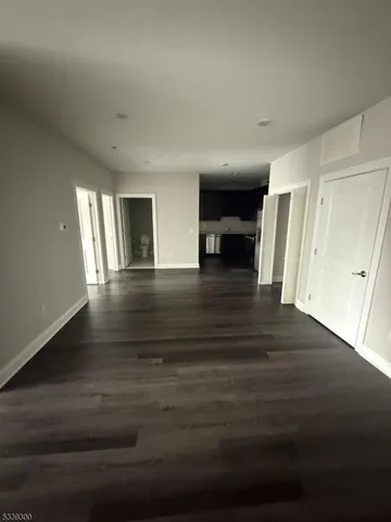 a view of an empty room with wooden floor and stairs