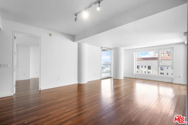 a view of an empty room with wooden floor and a window