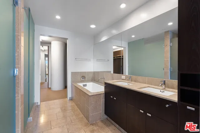 a spacious bathroom with a double vanity sink a mirror and a bathtub